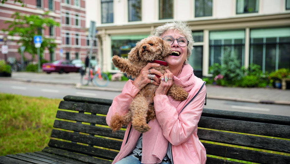 Lady lifting up dog on park bench