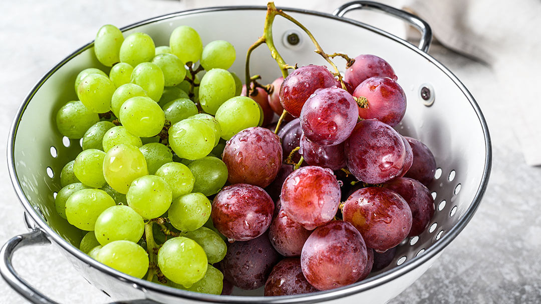 Red and green grapes in a colander
