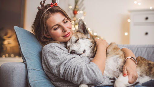 woman wearing antlers hugging her sleeping dog