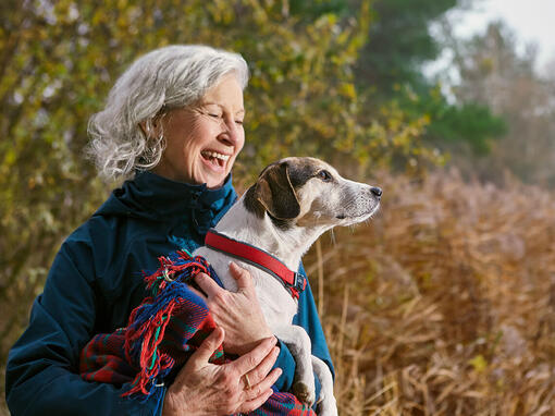 Woman holding dog in a blanket outside